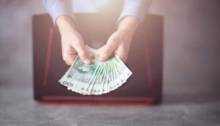 pożyczka. Polskie pieniądze trzymane przez bankowca w ręce., W ogólnopolskim badaniu „Sytuacja NGO-sów w czasie pandemii” ponad pół tys. organizacji wskazało najpoważniejsze obecnie zagrożenia dla swojej działalności. Kluczowym problemem, zwłaszcza w największych aglomeracjach, są kłopoty w zdobywaniu bieżących funduszy. Druga trudność to biurokracja administracji publicznej. To z kolei przeważnie występuje na wsiach i w kilkunastotysięcznych miastach. Spore niepokoje budzi też m.in. konkurencja, nadmierna kontrola organów państwa i konieczność wypłaty stałych wynagrodzeń pieniężnych. Badanie, przeprowadzone dla portalu zbiórkowego Szczytny-Cel.pl wśród 266 fundacji i 255 stowarzyszeń, wykazało, z czym najbardziej zmagają się organizacje pozarządowe w dobie pandemii. Podmioty mogły wskazać w ankiecie 5 głównych problemów. I najwięcej z nich, tj. 42,6%, podało trudności w zdobywaniu bieżących funduszy. – Pozyskiwanie środków na bieżące potrzeby zawsze było największym wyzwaniem dla organizacji pozarządowych. Natomiast pandemia zaostrzyła stale występujące w tym sektorze obawy, że nie uda się zdobyć niezbędnych środków do prowadzenia działalności. Mocno wpłynęły na to cięcia budżetowe w samorządach finansujących podmioty pożytku publicznego – komentuje dr Justyna Kościńska, adiunkt w Centrum Europejskich Studiów Regionalnych i Lokalnych na Uniwersytecie Warszawskim oraz członkini Stowarzyszenia „Miasto Jest Nasze”. Jak wykazał raport, trudności ze zdobywaniem bieżących funduszy przeważnie deklarują organizacje z miast liczących co najmniej 500 tys. mieszkańców – 55,1%. Problem ten głównie dotyka podmioty działające na rynku nie dłużej niż 5 lat – 48%, a także istniejące ponad 15 lat – 46,9%. Najczęściej wskazują go stowarzyszenia i fundacje wspierające seniorów – 45,9%, jak również lokalną społeczność – 45,8%. – Wydawałoby się, że duże miasta sprzyjają tego typu działalności, a właśnie tam badani najbardziej się skarżą. Wynika to z tego, że w takich aglomeracjach walczy o fundusze najwięcej stowarzyszeń i fundacji. Najtrudniej mają młode podmioty, które dopiero pracują na zaufanie. Jednak starsze organizacje też nie mają łatwo, bo ich atrakcyjność dla darczyńców z czasem spada – mówi Maciej Kamiński, Prezes Zarządu platformy zbiórkowej Szczytny-Cel.pl. Drugim najczęściej wskazywanym problemem jest biurokracja administracji publicznej – 35,1%. Jak tłumaczy dr Kościńska, reprezentujące ją podmioty działają w zupełnie inny sposób niż organizacje pozarządowe. Mają też odmienne potrzeby i ograniczenia. Dlatego ta bariera zawsze istniała, ale stała się bardziej widoczna w czasie pandemii. I jak wynika z badania, obecnie najczęściej zgłaszają ją najmłodsze organizacje, istniejące nie dłużej niż 5 lat – 44%, na wsiach i w miastach liczących do 19 tys. mieszkańców – 46,2%, na rzecz dzieci i młodzieży – 45,9%, a także dla lokalnej społeczności – 38,5%. – Z moich obserwacji wynika, że podmioty z mniejszym stażem bardziej dostrzegają biurokrację. To oczywiście nie znaczy, że jej nie ma, ale warto zrozumieć specyfikę pracy administracji publicznej i nauczyć się z nią funkcjonować. Oczywiście działając na wsiach i nawet w kilkunastotysięcznych miastach można mieć większe kłopoty natury prawno-administracyjnej, w tym słabszy dostęp do prawników, doradców podatkowych i innych specjalistów – zaznacza Maciej Kamiński. Trzecim zagrożeniem, jakie widzą dla siebie stowarzyszenia i fundacje, jest konkurencja ze strony innych organizacji – 32,6%. Najbardziej obawiają się jej podmioty działające już 11-15 lat – 35,4%, a także istniejące nie dłużej niż 5 lat – 32,8%. Ten problem najczęściej jest wskazywany w miastach mających powyżej 500 tys. mieszkańców – 39,7%. Przeważnie zgłaszają go organizacje zajmujące się sprawami lokalnej społeczności – 36,5%. – W największych polskich miastach rzeczywiście występuje bardzo duża konkurencja wśród organizacji, ponieważ jest ich wiele i wszystkie mocno starają się pozyskać fundusze, zwłaszcza u władz lokalnych. W mniejszych miejscowościach często łatwiej jest się przebić ze swoją inicjatywą, szczególnie działając jako jeden z niewielu tego typu podmiotów na rzecz miejscowej społeczności – stwierdza dr Kościńska. Na czwartym miejscu na liście największych zagrożeń dla organizacji pozarządowych jest nadmierna kontrola organów państwa – 31,9%. Jak podkreśla Maciej Kamiński, w czasie pandemii organy państwowe dużo rzadziej je kontrolowały niż wcześniej. Dlatego ten czynnik ma mniejsze znaczenie niż trzy główne problemy, mocniej związane z walką o przetrwanie na rynku. Natomiast fakt, że taka bariera wciąż jest jedną z czołowych w prowadzeniu działalności dobroczynnej, nie jest dobrą informacją. – Warto pogłębić to badanie, by ustalić, na czym polega nadmierna kontrola. Pojawia się pytanie, czy chodzi o naciski, nękanie, utrudnianie lub wręcz uniemożliwianie działań organizacjom, których cele nie są po drodze organom państwa z powodów ideologicznych czy podzielanych wartości. Myślę tutaj przede wszystkim o podmiotach wspierających uchodźców i wszelkie wykluczane grupy ze względu na jakikolwiek czynnik, np. preferencje seksualne – zwraca uwagę dr hab. Małgorzata Molęda-Zdziech, kierownik Katedry Studiów Politycznych ze Szkoły Głównej Handlowej w Warszawie. Piątym wskazywanym przez badanych obciążeniem jest wypłata stałych wynagrodzeń pieniężnych – 30,7%. Jak zauważa ekspert z platformy zbiórkowej Szczytny-Cel.pl, pandemia najmocniej uwypukliła problemy z płynnością finansową tam, gdzie one już wcześniej istniały. Dlatego jest to postrzegane jako jeden z największych problemów. – Nie każda organizacja zatrudnia pracowników, którym musi płacić pensje. Niemniej podmioty będące pracodawcami borykają się z tym problemem, jeżeli jednocześnie mają kłopoty z pozyskiwaniem funduszy na bieżące działania. Jest to powiązane z najczęściej wskazywaną przez ankietowanych barierą – zauważa dr Justyna Kościńska. Dość długą listę problemów i zagrożeń, z jakimi spotykają się NGO-osy, zamyka brak zainteresowania dziennikarzy ich bieżącymi działaniami – 13,1%. Podobne wyniki mają takie kwestie, jak niekorzystny wizerunek organizacji pozarządowych w mediach i w opinii społeczeństwa – 13,8%, a także trudności w dostępie do lokalu potrzebnego do prowadzenia działalności – 14%. – Działania organizacji pozarządowych najczęściej stają się tematem dla dziennikarzy dopiero, gdy można pokazać coś sensacyjnego. Dlatego warto zwrócić uwagę na konieczność podejmowania działań komunikacyjnych w mediach społecznościowych, które umożliwiają docieranie z przekazem do wybranych grup społecznych i pozyskiwanie ich zaufania. To z kolei konieczne jest przy prowadzeniu akcji fundraisingowych – przekonuje dr Molęda-Zdziech. Natomiast dr Kościńska uważa, że ww. wyniki mogą oznaczać, iż zainteresowanie mediów działaniami organizacji pozarządowych jest wystarczające. Oczywiście warto poprawić sytuację, zwiększając ich popularność w środkach masowego przekazu. – Trudności lokalowe dotyczą zaledwie 14% badanych organizacji. To wskazuje, że obecnie fizyczna przestrzeń coraz częściej nie jest konieczna do podejmowania aktywności. Oczywiście wygląda to różnie w zależności od regionu i pola działania. Niemniej w praktyce znacznie większym problemem bywa utrzymanie personelu, w tym pracowników i wolontariuszy, co znalazło swoje miejsce w połowie ww. listy zagrożeń – podsumowuje ekspertka ze Szkoły Głównej Handlowej w Warszawie. Badanie pt. „Sytuacja NGO-sów w czasie pandemii” zostało przeprowadzone metodą CAWI przez UCE RESEARCH i SYNO Poland dla portalu zbiórkowego Szczytny-Cel.pl. Wzięło w nim udział 521 podmiotów pożytku publicznego z 16 województw. NGO